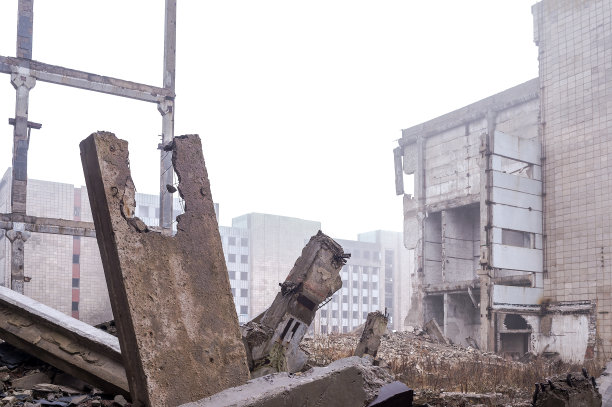 在雾中，一堆破碎的大桩、破碎的板和碎片映衬着一座被摧毁的建筑。背景图片下载