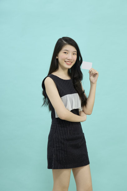 愉快的兴奋惊讶的年轻女子与信用卡在蓝色的背景图片下载