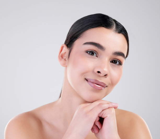 一个迷人的年轻女子在灰色背景下摆姿势的工作室肖像图片下载