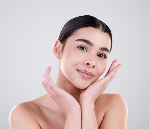 一个迷人的年轻女子在灰色背景下摆姿势的工作室肖像图片下载