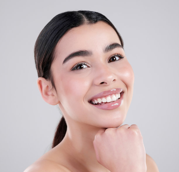 一个迷人的年轻女子在灰色背景下摆姿势的工作室肖像图片下载