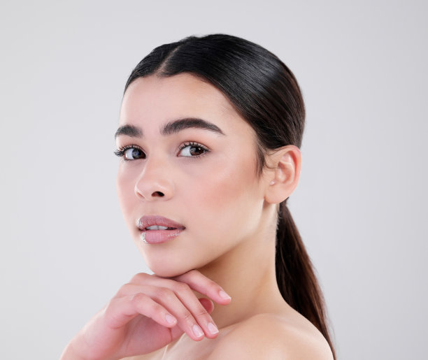 一个迷人的年轻女子在灰色背景下摆姿势的工作室肖像图片下载