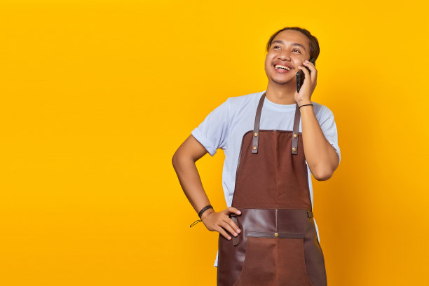 照片上，笑容满面的亚洲年轻人在黄色背景下用智能手机聊天图片下载