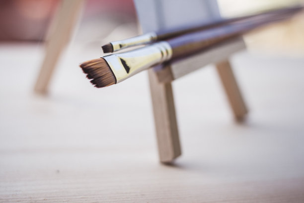 干净的毛笔在木制的迷你画架与空白的纸，艺术和灵感的概念图片下载