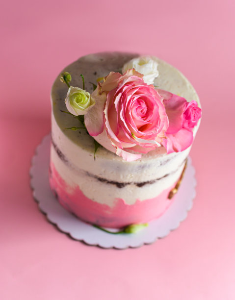 用粉色背景上的天然玫瑰装饰的蛋糕。有选择性的重点图片下载