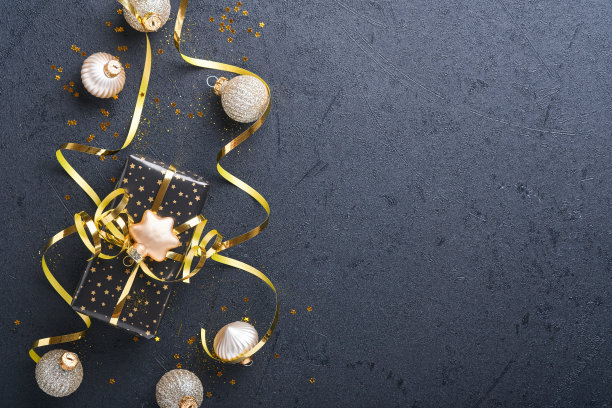 假日礼品盒或礼品带，金色的纸屑和金色的小玩意在黑色的背景上。神奇的圣诞贺卡。圣诞装饰。边界设计。模拟。前视图。图片下载