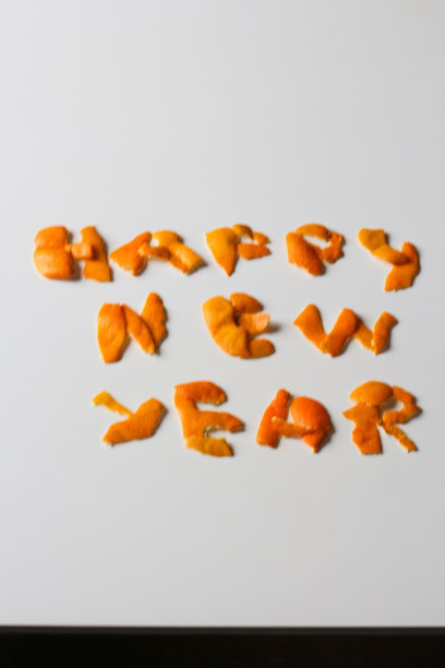 散焦的新年词由橙色干皮显示在灰色的背景上。装饰为除夕夜，概念。贺卡。文本和DIY字母。边境。孤立。垂直的。的焦点图片下载