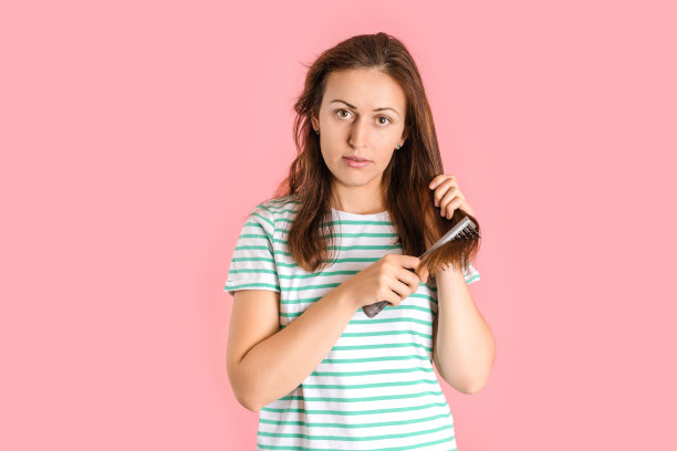 一个深色头发的女人在粉红色的背景上梳头图片下载