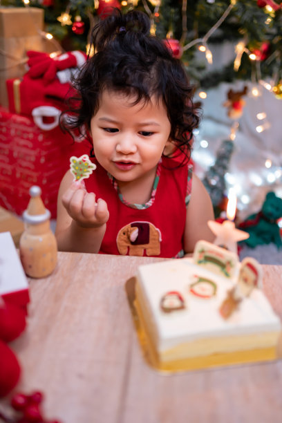 快乐的亚洲小女孩与圣诞蛋糕在家里与家人的寒假。图片下载