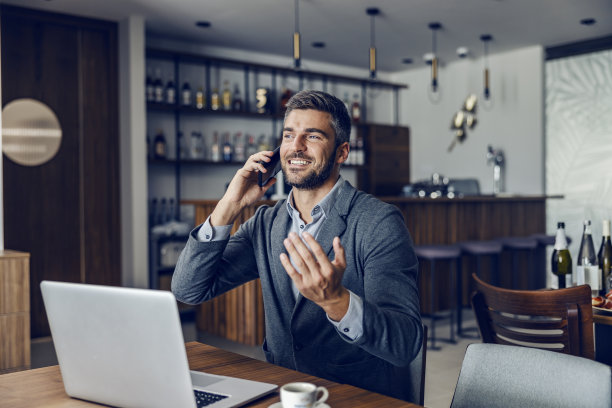 一个友好的忙碌的人正坐在工作友好的咖啡馆和同事们通电话。桌子上有一台笔记本电脑。一个商人在咖啡馆讲电话图片下载