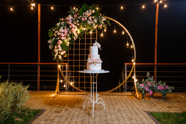 婚礼拱门的背景上是漂亮的白粉色婚礼蛋糕。图片下载