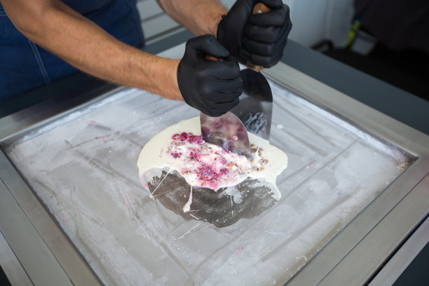 在冷冻锅里炒冰淇淋卷。卷冰淇淋，手工制作的冰淇淋甜点。用钢制冷却锅煎制冰淇淋机。图片下载