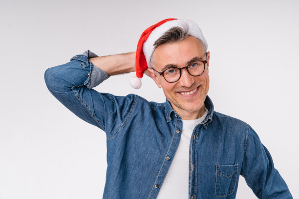 沉思开朗的白人成年中年男子在圣诞老人红色的帽子庆祝新年前夕的圣诞节时间隔离在白色的背景图片下载