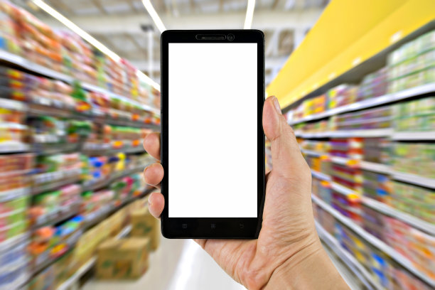 手持黑色智能手机或移动电话与剪接路径和超市商店的背景模糊。图片下载