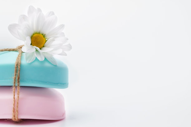 手工制作的天然肥皂条和白色背景上的花朵图片下载