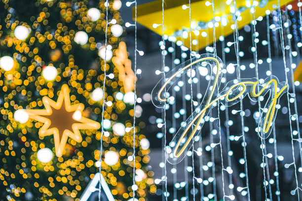 圣诞装饰灯以爱心字的形状和祝福图片包裹装饰在绿色圣诞树的散景背景装饰圣诞节和新年期间。图片下载