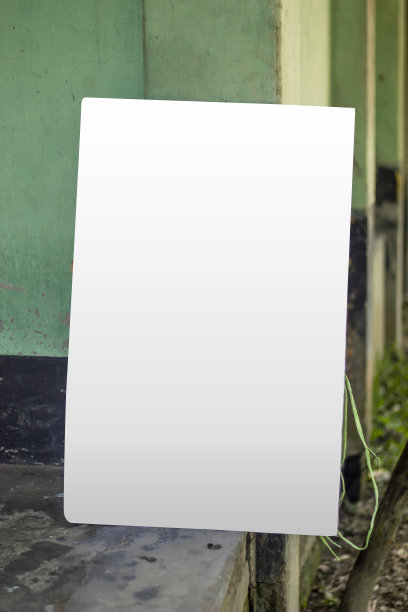 一块空白的白色招牌靠在旧墙上，一根杆子，背景模糊。图片下载