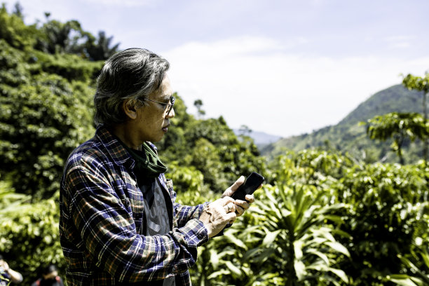 老年人在森林中行走时使用手机图片下载