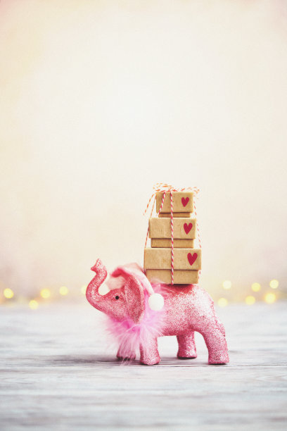 可爱的圣诞背景与闪闪发光的粉红色大象扛着一堆圣诞礼物图片下载