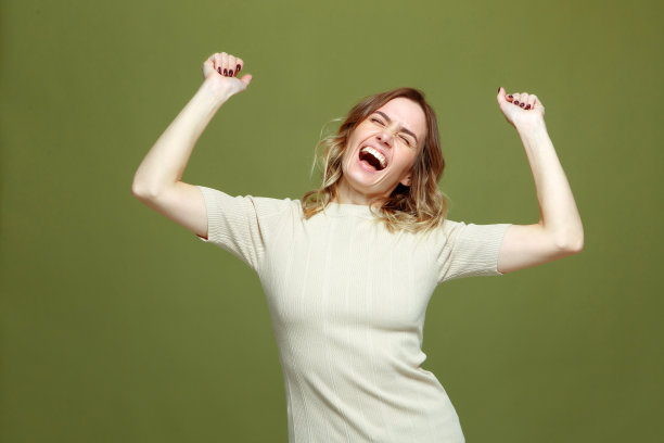 欣喜若狂的成功年轻女性举起手臂庆祝胜利，兴奋地尖叫，幸福。财富的概念图片下载