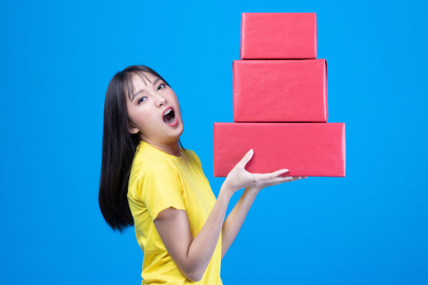 肖像中的快乐微笑的女孩在随意地拿着礼品盒和表情脸孤立在黄色的背景图片下载