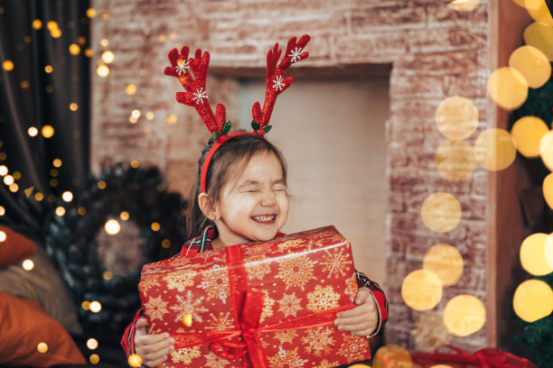 穿着红色睡衣的女孩抱着一个带着礼物的大盒子图片下载
