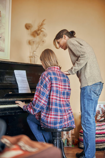 一位年轻的女性正在舒适的家中学习弹钢琴图片下载