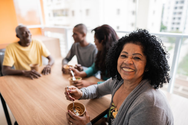 一位年长女性和家人在家里吃饭的照片图片下载