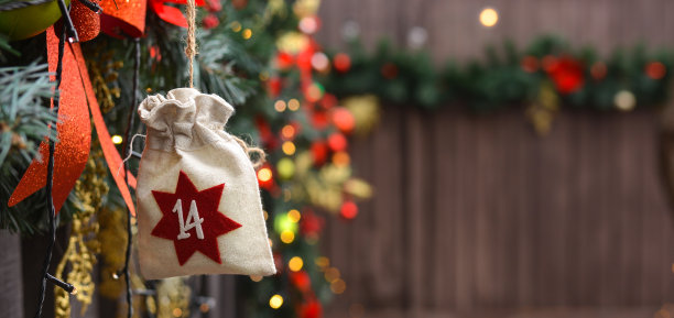 以环保袋的形式挂在门廊圣诞装饰的背景上的降临节日历。圣诞礼物和任务。空荡荡的木制圣诞背景。本空间图片下载