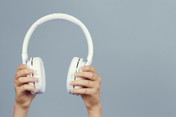 手握现代白色无线耳机在浅灰色的背景图片下载