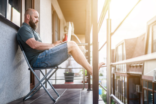 成熟的男人在家里的阳台工作图片下载