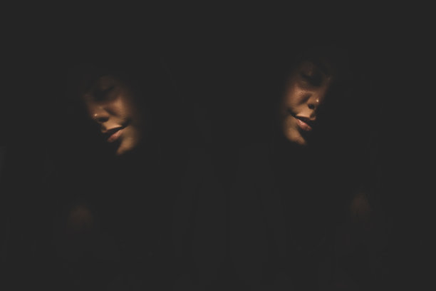 年轻女子闭着眼睛在黑暗中微笑，在镜子中反射图片下载