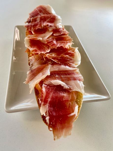 早餐烤火腿，面包放在白色的盘子里，放在白色的桌子上。特写镜头图片下载