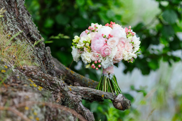 一个精致和非常美丽的婚礼花束玫瑰，牡丹，牡丹和氢化背景上的绿色植物。粉色和白色的新娘花卉。手柄装饰有蕾丝和syvmolichnym钥匙图片下载