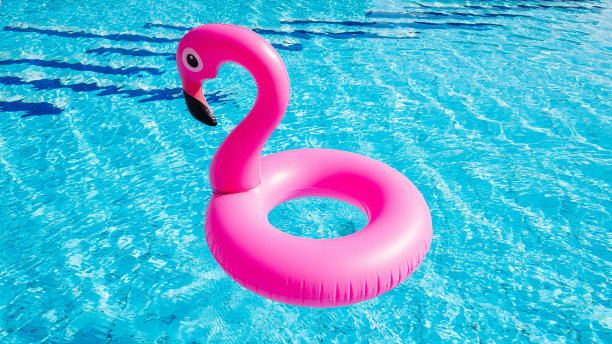 火烈鸟图标。粉红色充气火烈鸟在游泳池水的夏季海滩背景。最小的夏天的概念。图片下载