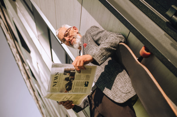 一位头发花白的商人正在看报纸，看上去很专注图片下载