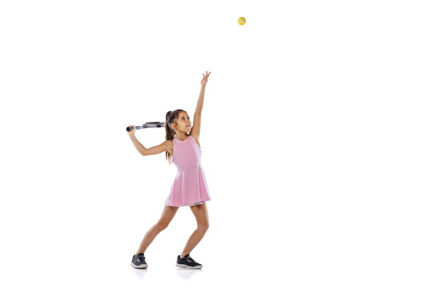 女网球初学者在白色摄影棚里孤立地打网球的摄影棚里拍摄。运动、学习、童年观念图片下载