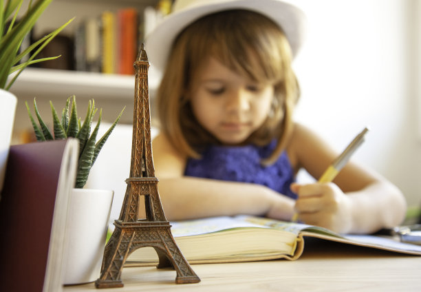 可爱的小女孩在她卧室的书桌前做作业-小女孩在日记中想象去巴黎的旅行-童年，旅行和教育的概念图片下载