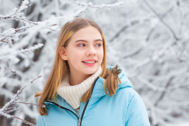 美丽快乐的十几岁女孩肖像行走在雪白色的冬天的一天在雪森林图片下载