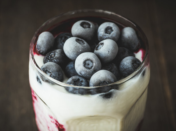 一杯希腊白酸奶和冰冻蓝莓。有选择性的重点。景深浅。图片下载