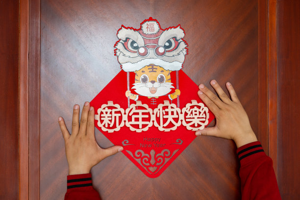 一名男子在门上贴了一个2022年虎年的吉祥物，没有标志没有商标翻译的中文是新年快乐素材图片