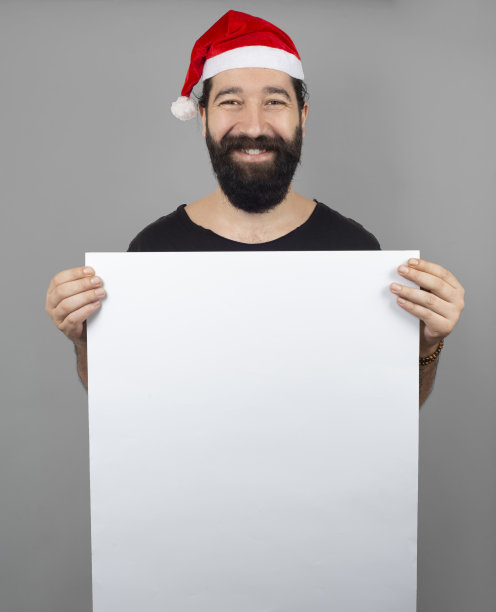 带着圣诞帽的微笑男人的肖像拿着白纸图片下载