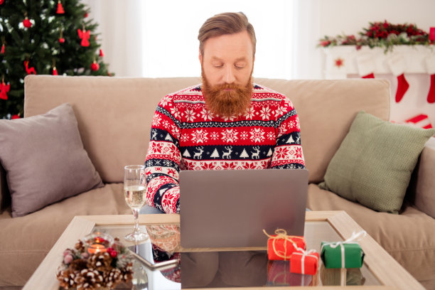 照片年轻严肃专注的男性商人工作在笔记本电脑远程在家里庆祝新年圣诞节图片下载