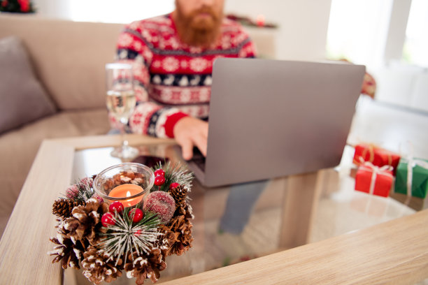 新年气氛照片的人用电脑附近的节日装饰温暖的蜡烛云杉松树装饰冬季假期图片下载