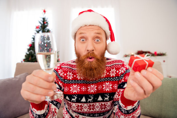 照片中的年轻人惊讶的震惊的惊讶哇在室内喝酒干杯祝酒辞拿礼盒新年图片下载