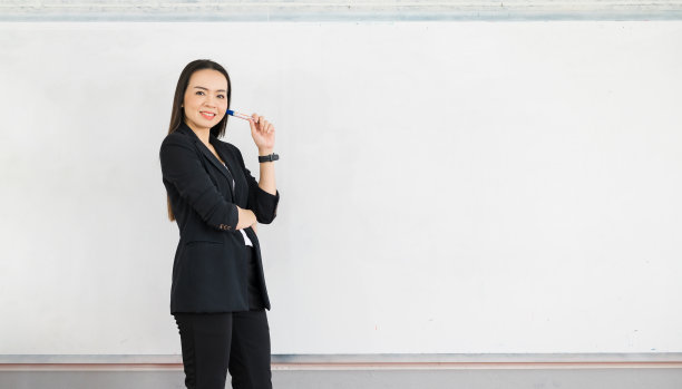 一名身穿黑色服装的亚洲女教师站在大学教室前的白板前。教育理念，毕业，大学教师生涯图片下载