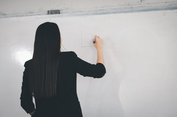 一名身穿黑色服装的亚洲女教师站在大学教室前的白板前。教育理念，毕业，大学教师生涯图片下载