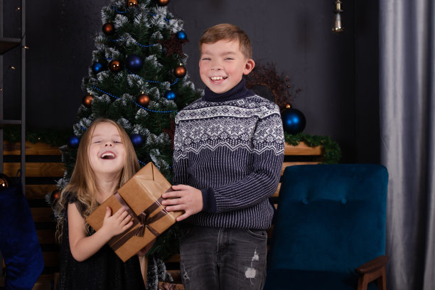 圣诞树旁迷人的金发小男孩和小女孩。兄弟姐妹庆祝新年图片下载