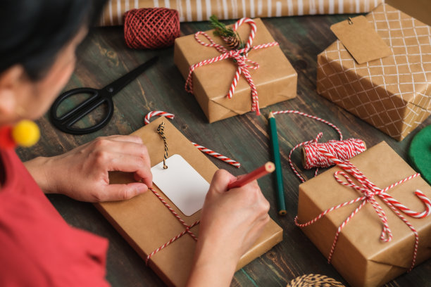 女人写礼物标签，并附在圣诞礼物木桌子上图片下载