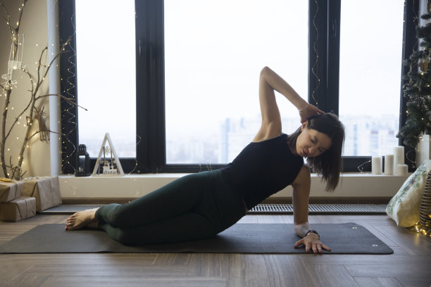 年轻女子在圣诞氛围的家中进行瑜伽健身图片下载